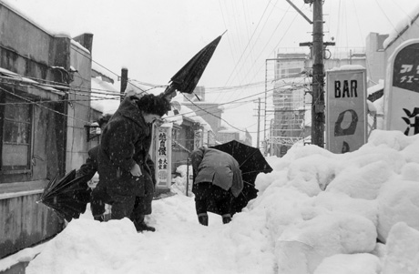 三八豪雪　電線をくぐって通る市民（福井市）