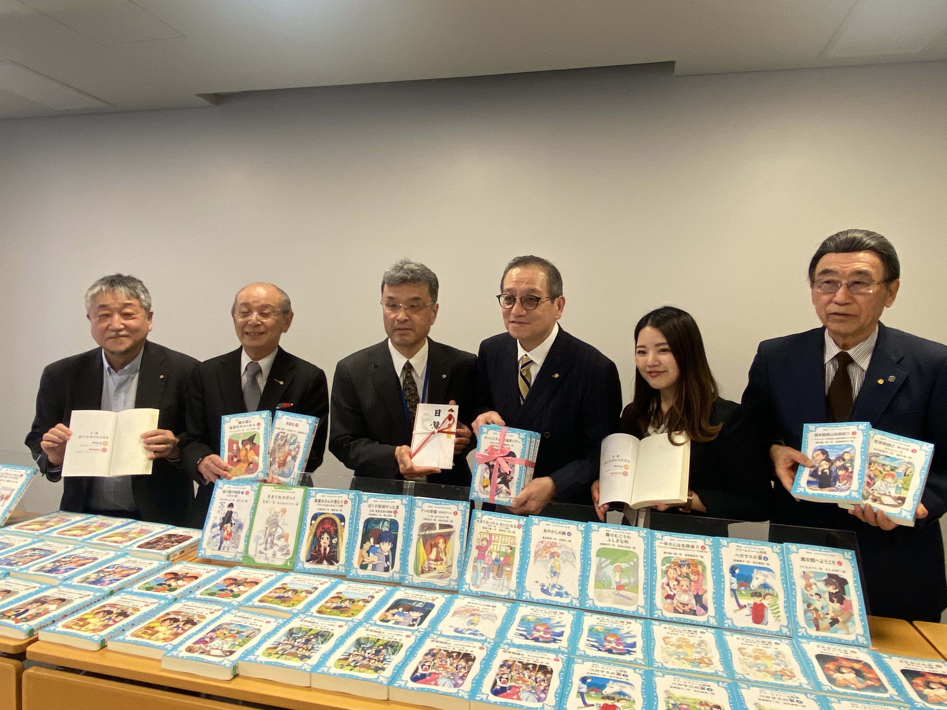 寄贈の本を前において代表者と撮った写真